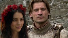 a man and woman dressed up in medieval clothing with red flowers on their head, standing next to each other