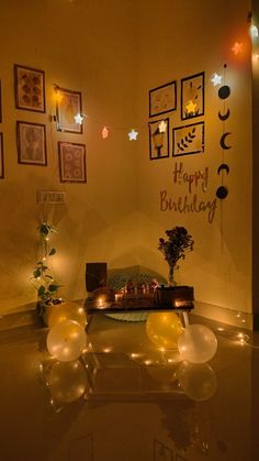 a birthday party with balloons, candles and pictures on the wall above it is lit up