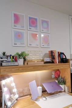 a desk with two laptops on it in front of three framed pictures and other office supplies