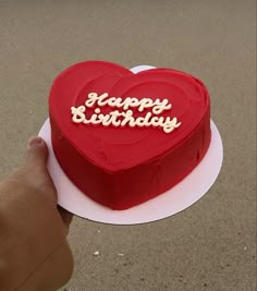 a heart shaped cake with the words happy birthday on it being held by someone's hand