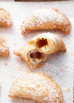 several pastries are on a baking sheet with powdered sugar and jelly fillings