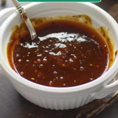 a white bowl filled with sauce sitting on top of a wooden table next to a green sign