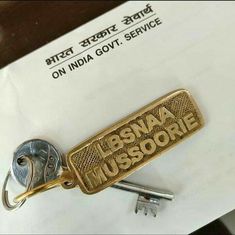 a metal keychain with the words bsna mussorie written in gold on it