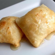 two pastries sitting on top of a white plate covered in melted cheese and sauce