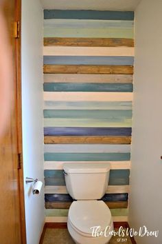 a white toilet sitting in a bathroom next to a wall with wooden planks on it