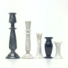 marble vases are lined up in a row on a white surface, with one black and the other white