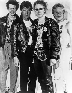 an old black and white photo of four men in leather jackets, one wearing sunglasses