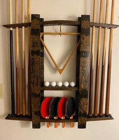 a rack with several different types of paddles on it and some balls in the back