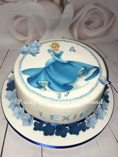 a white cake decorated with blue flowers and a princess figure