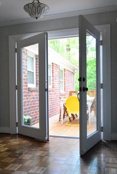 an open door leading to a patio with chairs and table in the back ground area