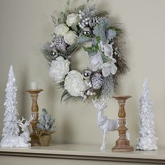 a christmas wreath on top of a mantle next to candles and other holiday decor items