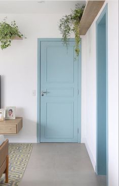 a living room with a blue door and two planters on the wall next to it