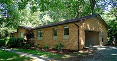 a small brick house sitting in the middle of a park with lots of trees around it