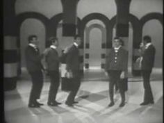 four men in suits are standing together on the set of an old tv show,