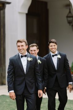 three men in tuxedos are walking towards the camera