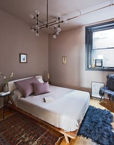 a bed sitting next to a window on top of a hard wood floored floor