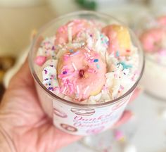 a hand holding a cup filled with ice cream and sprinkles