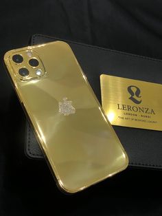 a gold iphone case sitting on top of a black bag next to a card holder