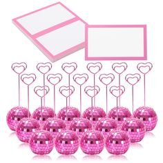 a bunch of pink disco balls with hearts on them next to a white card board