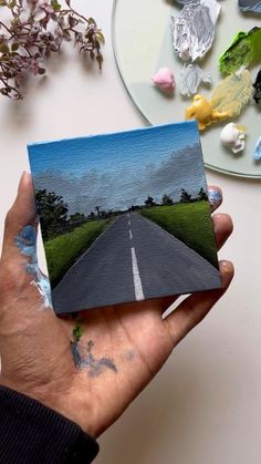 a person holding up a piece of paper with an image of a road on it