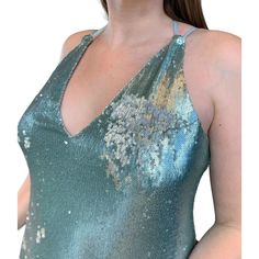 a woman wearing a green dress with sequins on the bottom and back, standing in front of a white background