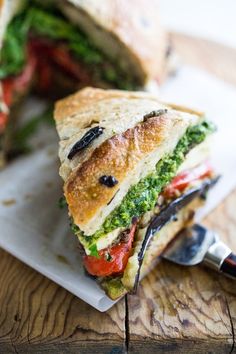 a cut in half sandwich sitting on top of a white plate next to a knife