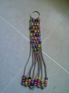 several multicolored beads hang from a metal hook on a tile floor in a room