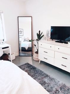 a bedroom with white furniture and a large mirror