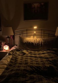 a bed with a plaid comforter and two candles on the headboard in front of it