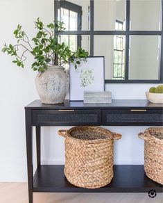 two baskets are sitting on a table with a mirror and plant in front of it