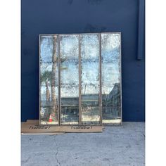 three mirrored windows sitting on the side of a building with palm trees reflected in them