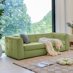 a living room scene with focus on the couch and rugs in front of the window