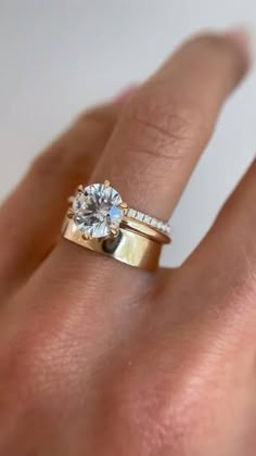 a woman's hand with a diamond ring on top of her finger and an engagement band