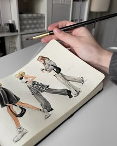 a person holding a pencil and drawing on top of a book with pictures of women