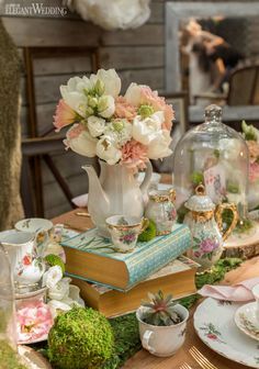 a table topped with books and vases filled with flowers next to an open book