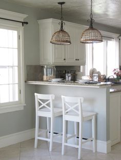 a kitchen with white cabinets and two stools