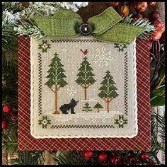 a cross stitch christmas ornament hanging from a tree