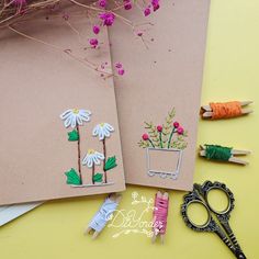 two notebooks with flowers on them next to scissors and some thread spools