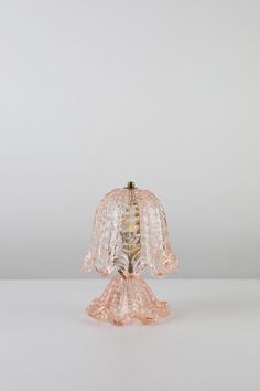 a pink glass table lamp sitting on top of a white surface