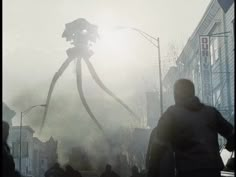 people walking down the street in front of a giant spider - man statue on a foggy day