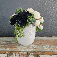 a white vase filled with flowers on top of a wooden table