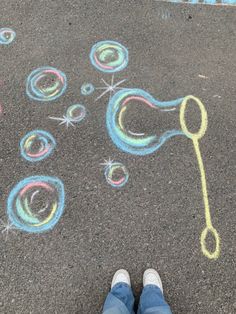 someone standing in front of a chalk drawing on the ground with scissors and bubbles drawn on it