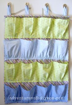 a blue and green wall hanging on the side of a wall with clothes pins attached to it