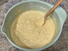 a mixing bowl filled with batter on top of a granite counter next to a wooden spoon