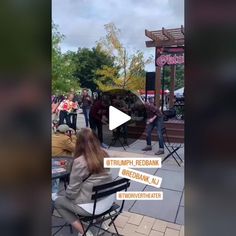 a woman sitting in a chair on top of a sidewalk next to a group of people