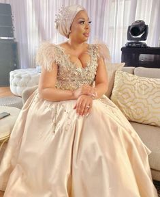 a woman sitting on top of a couch wearing a dress and headpiece with feathers