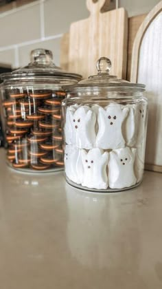 two glass jars filled with marshmallows sitting on top of a kitchen counter