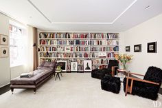 a living room filled with furniture and bookshelves covered in lots of bookcases