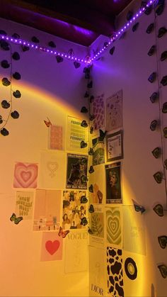 there is a wall with many pictures on it and purple lights hanging from the ceiling