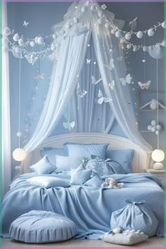 a bed with blue sheets and white curtains in a room that has butterflies hanging from the ceiling